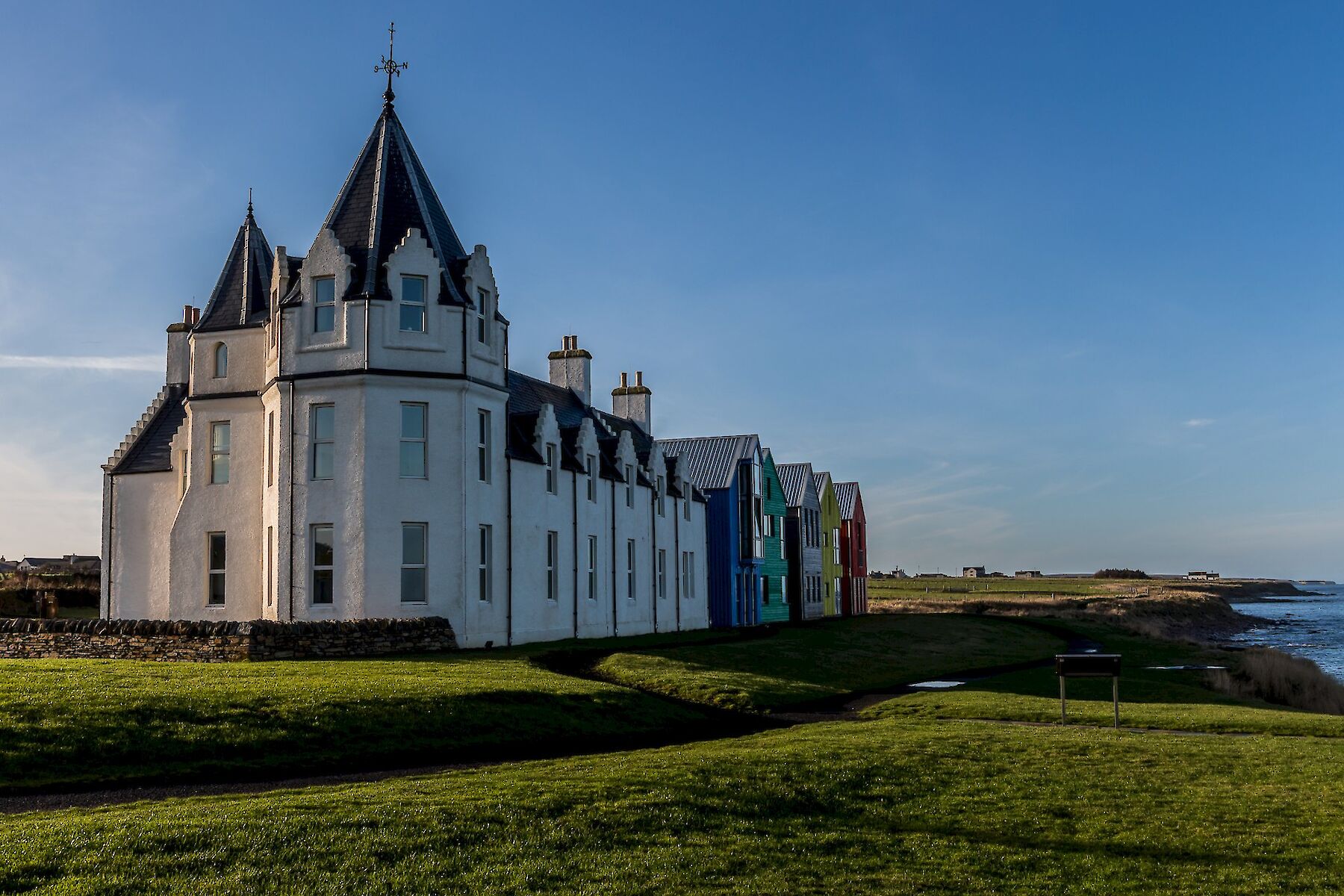 John O'Groats image: Sunset shot of the colourful houses and hotel on the shore at John O Groats