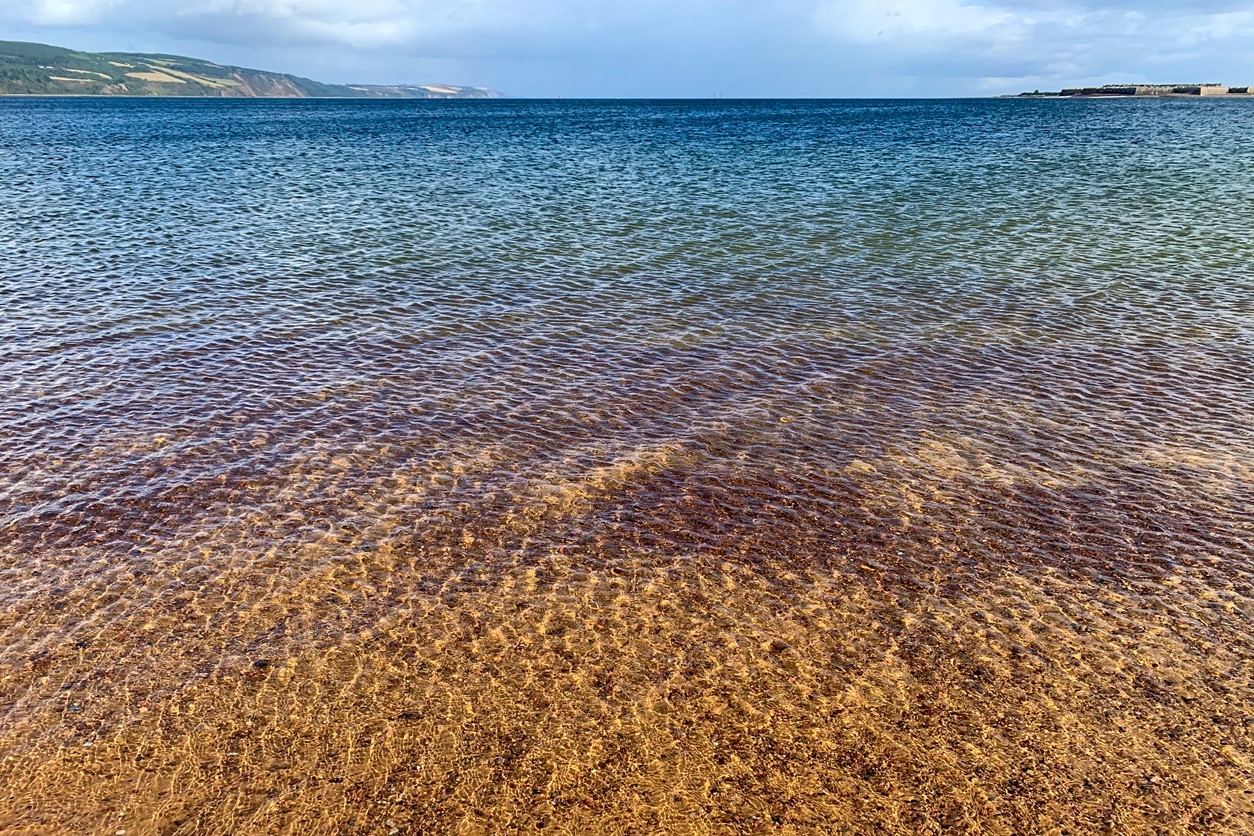 Rippling water stretches out in front everywhere as the wind catches it, but it's still possible to see the colours of the sandy floor below.