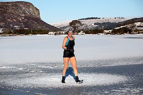 Image: Woman in swimming suit strides across a frozen loch.