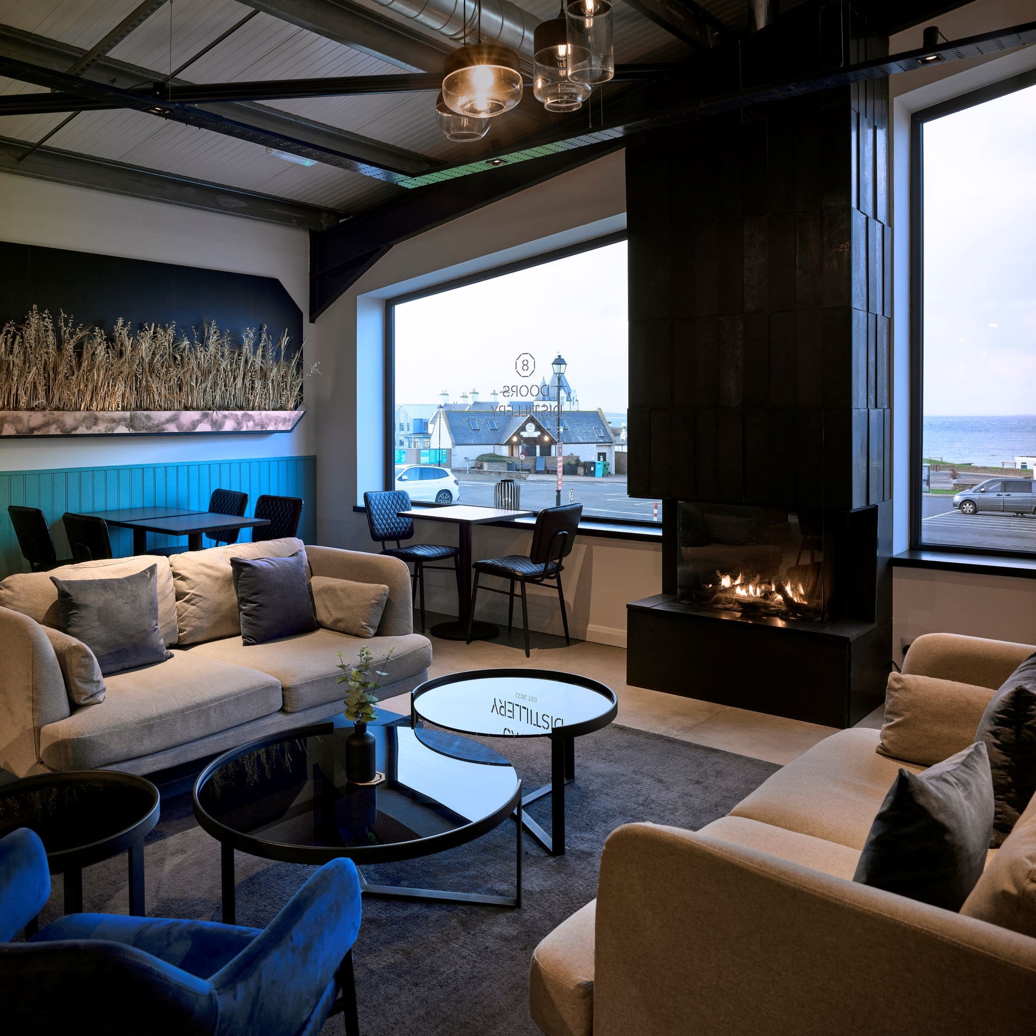 The lounge in 8 Doors Distillery, with a romentic open fire, looking out onto the Pentland Firth and rest of John O'Groats, on the North Coast of the Scottish Highlands. 