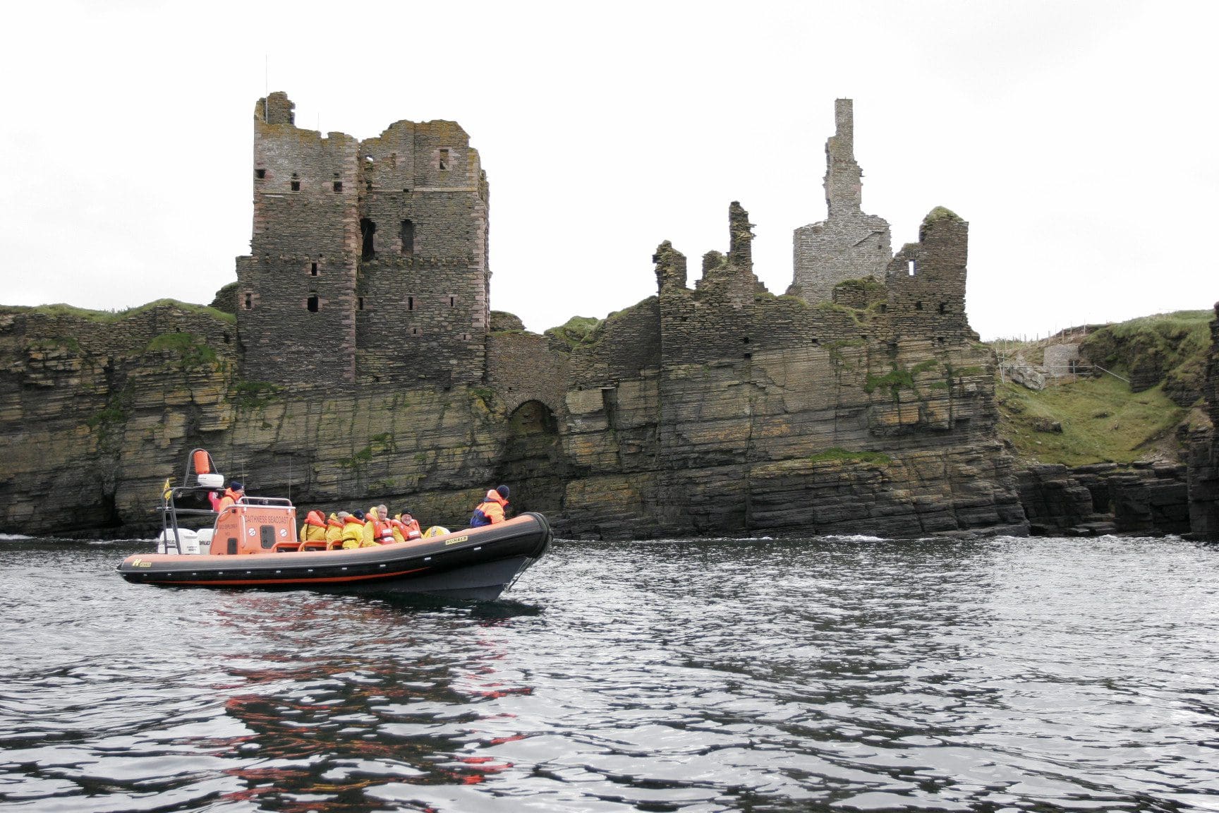 A boat from Caithness Sea Tours sailing past Castle Sinclair Gringoe on a tour of the East Coast of the North Highlands. 