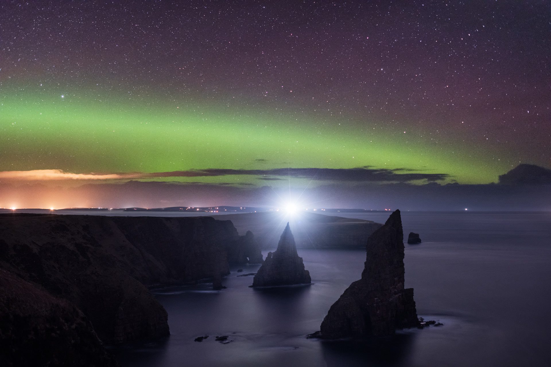 A night scene with an Aurora over the Duncansby Stacks in the foreground.
