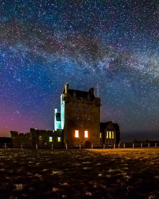 Milkyway and northern lights night sky over Ackergill Tower, Caithness, North Highlands