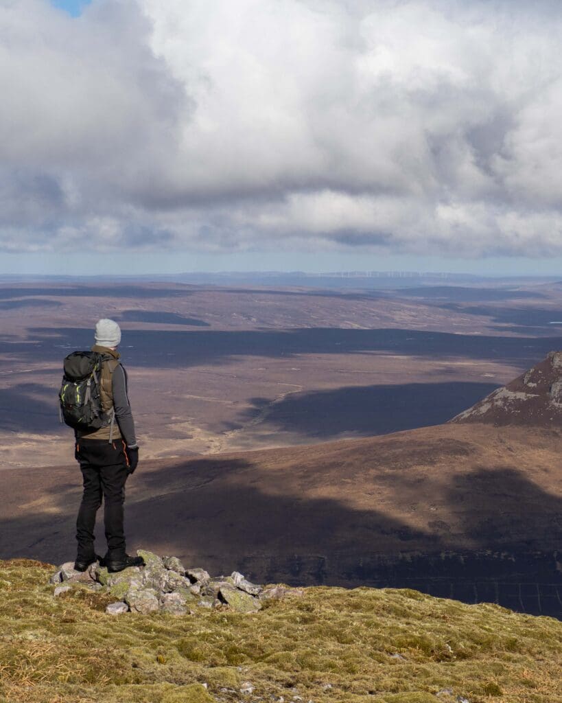 A person stands atop Morven, looking over the land covered in heather. In Sutherland, Scotland. nature and outdoors in the North Highlands