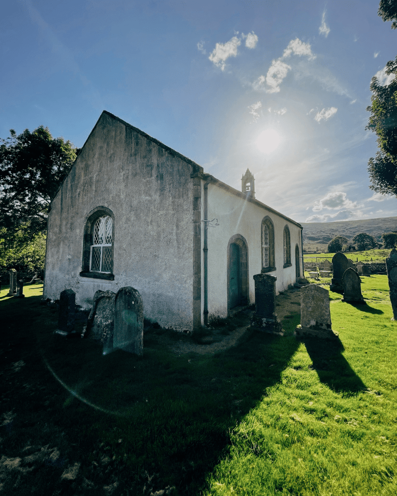 Croick Curch, located in Sutherland, with the sun behind the church and some grve stones.