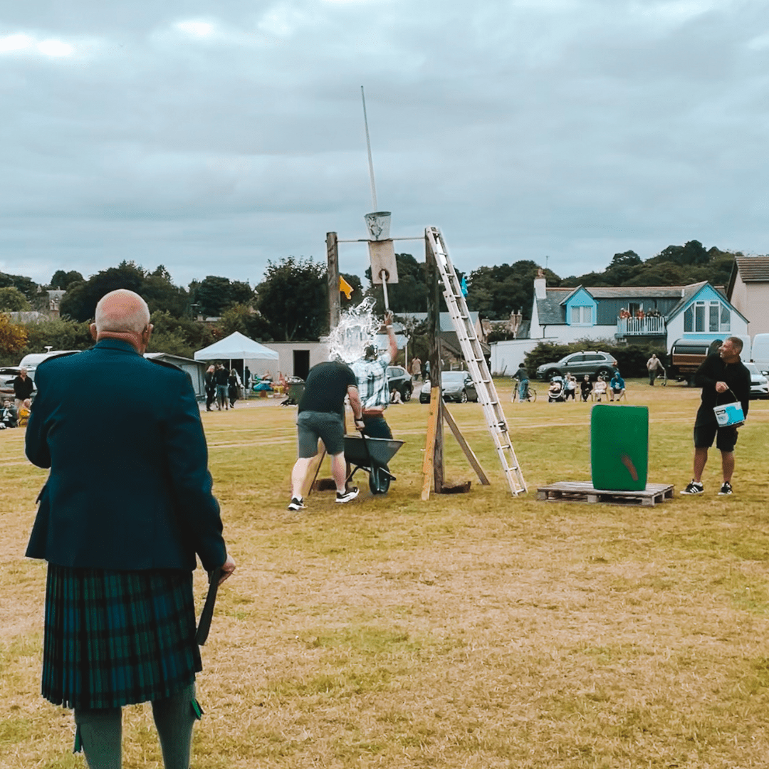Group playing 'tip the bucket' game at Dornoch Highalnd games, East Coast of Sutherland, North Highlands
