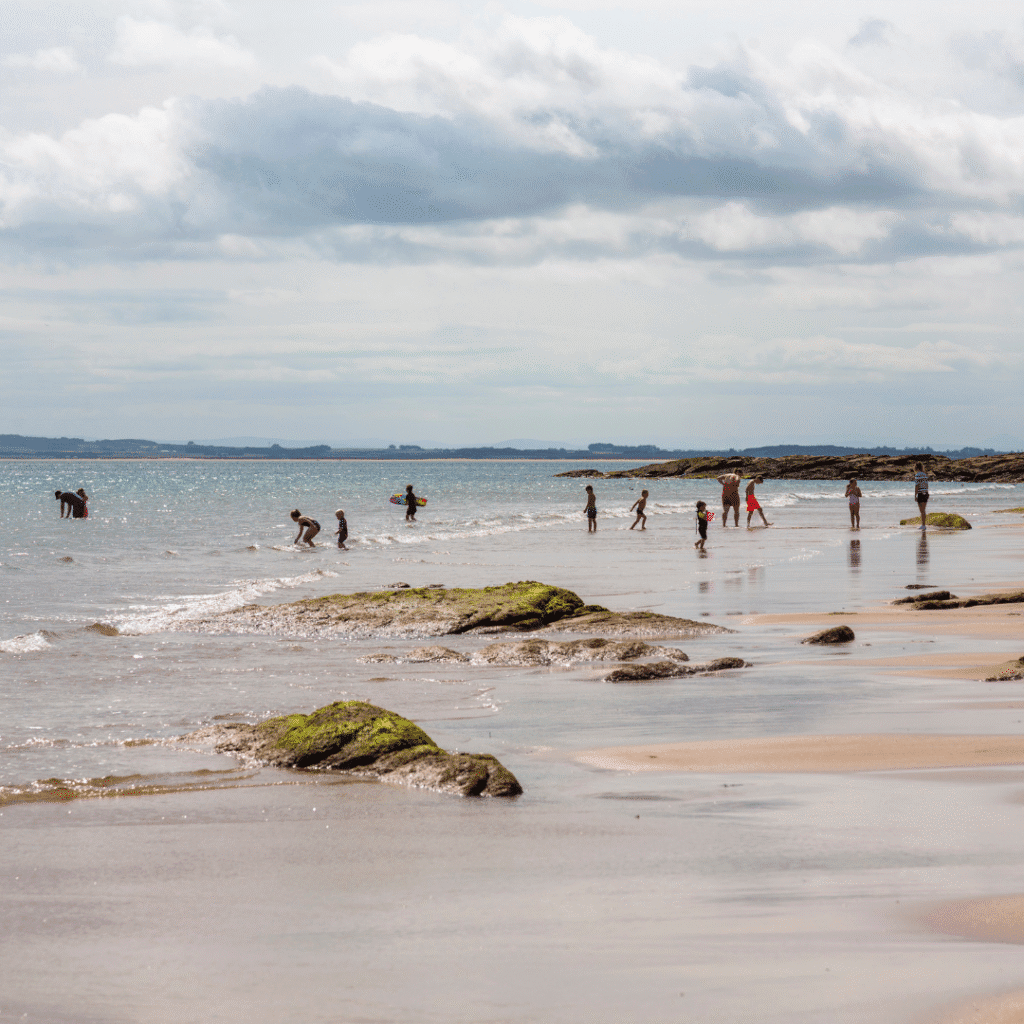 A group of people playing at Embo Beach, the weather is good. Sutherland, Scotland. nature and outdoors in the North Highlands