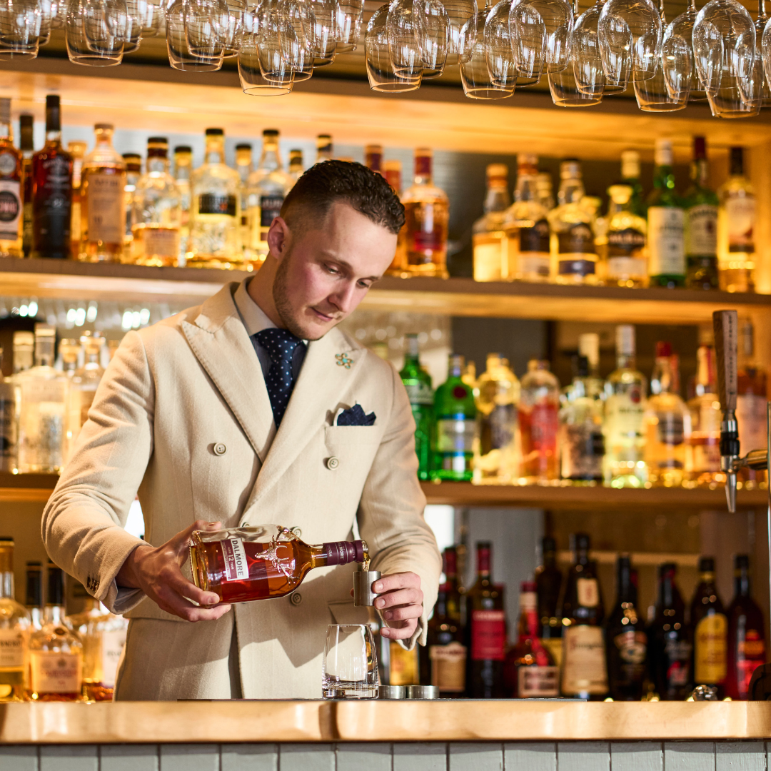 Bartender pouring local made whisky at Kylesku Hotel, West Sutherland, North Highlands