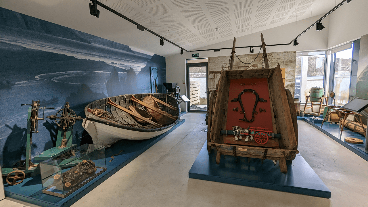 An interior view of Strathnaver Museum, in Sutherland, Scotland. A rowing boat and old cart can be seen