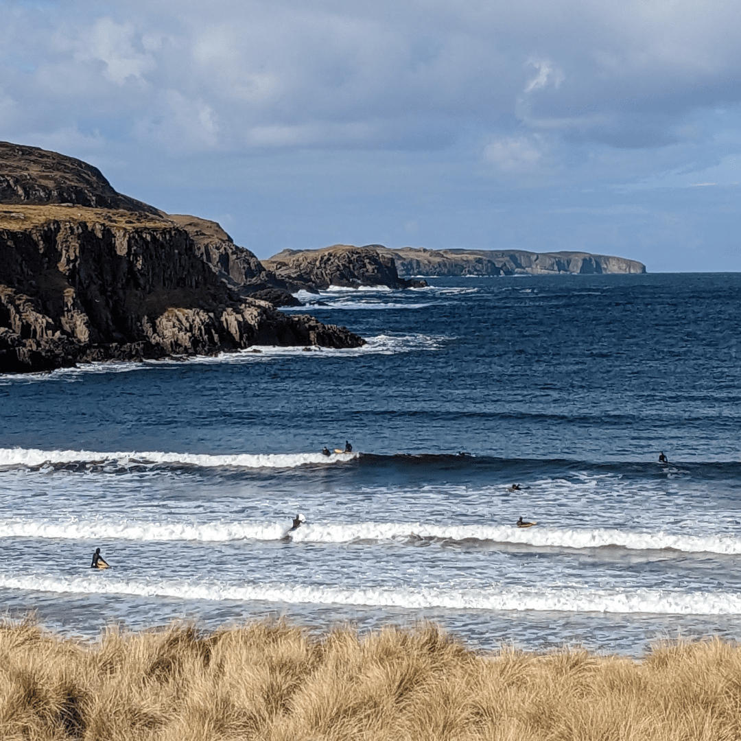 A group of surfers riding waves at Strathy, Sutherland, North Highlands. Watersports North Highlands.