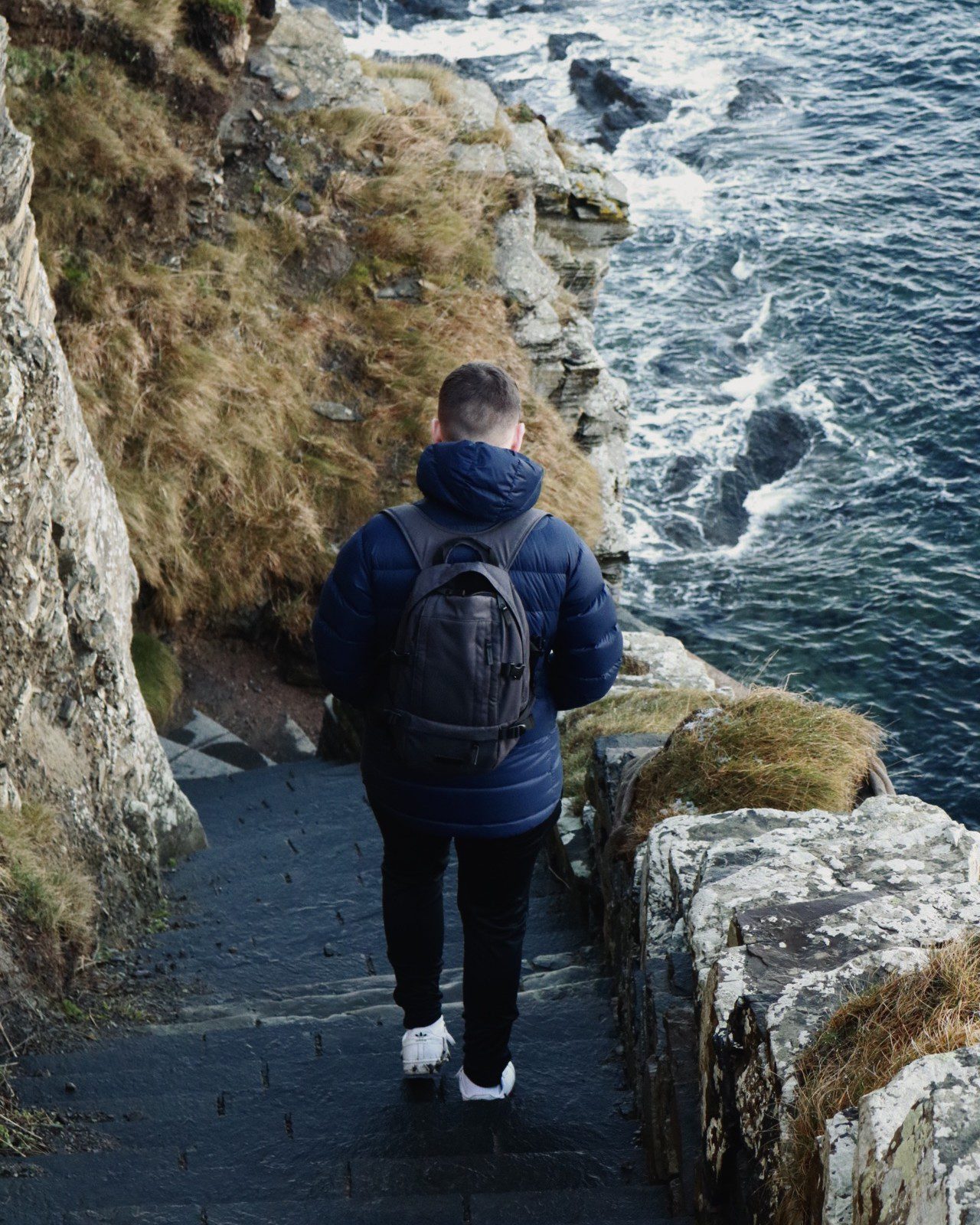 A man viewed from the back walking down Whaligoe Steps, in Caithness, Scotland. Attractions and landmarks.
