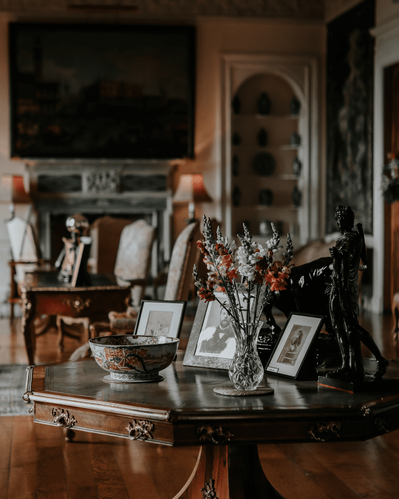 The interior of Dunrobin Castle, a small table with framed pictures and flowers. Attractions and landmarks.