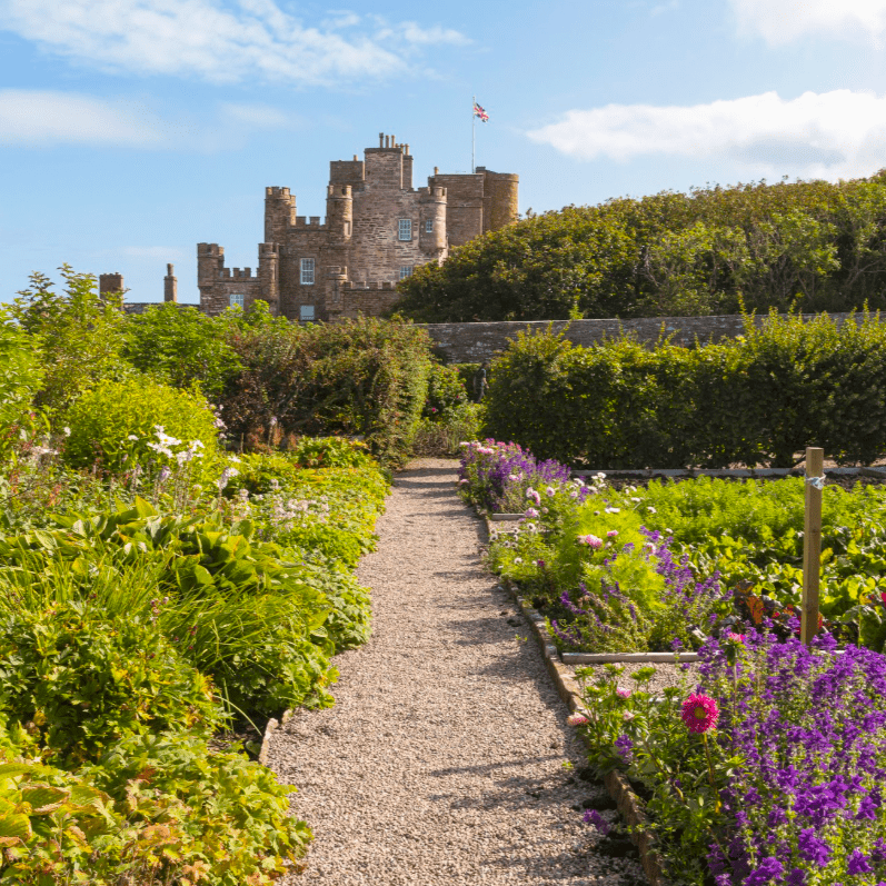 The Castle and Gardens of Mey, taken from the lush gardens, blooming with summer flowers and green grass, Mey, Caithness, North Highlands