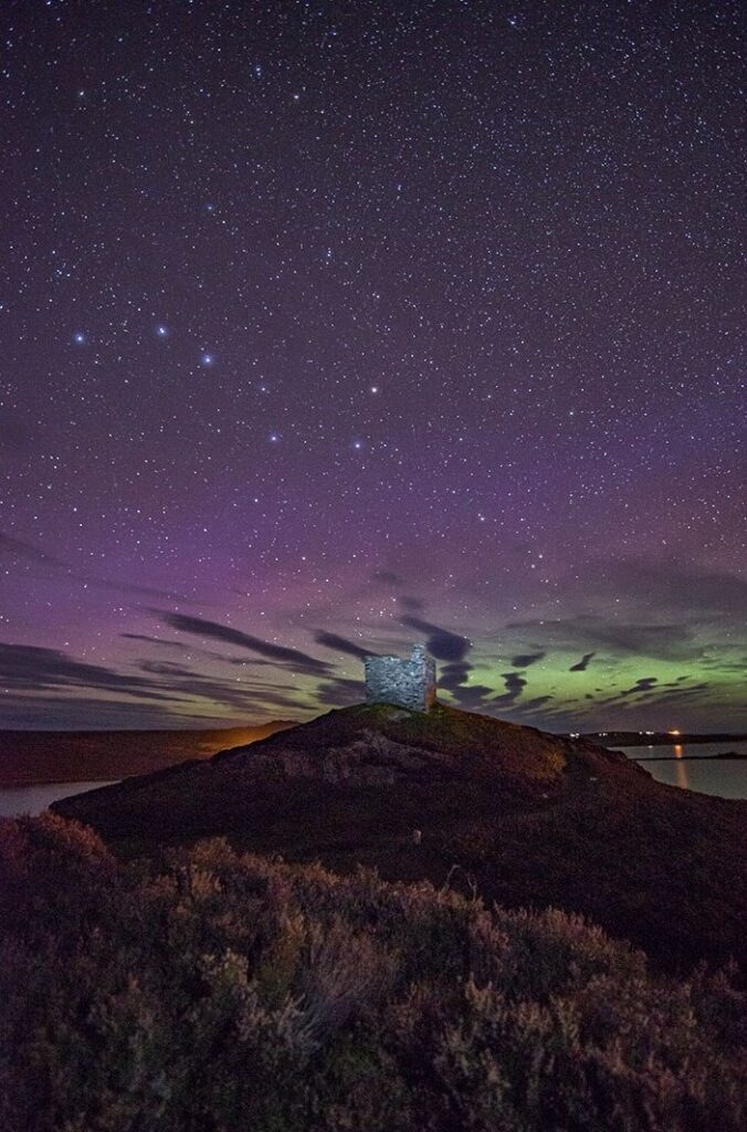 Aurora Borealis and stars in the night sky over Castle Varrich, Tongue, near the North Coast 500, Sutherland. Image by Gary MacLeod.