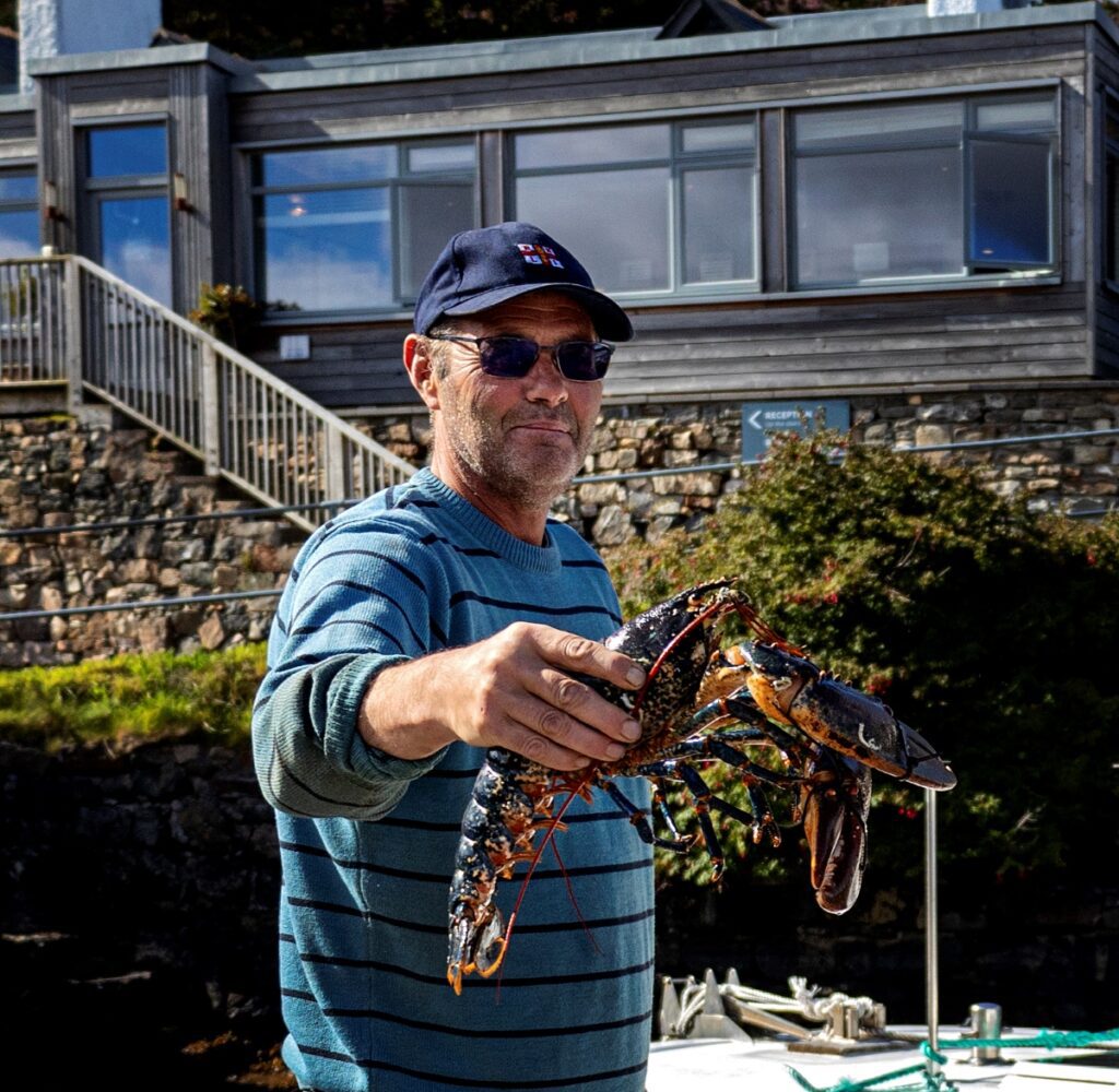 A fisherman holding a fresh lobster, locally landed outside the Kylesku Hotel in North West Sutherland.