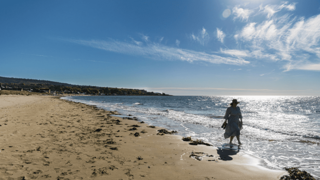 A woman walks through the waves bare foot, in Golspie beach, North Highlands