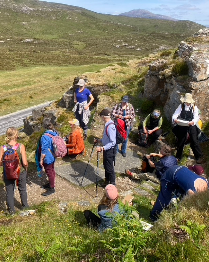 A group of people gathered around their tour guide, in the North West Highlands, Scotland