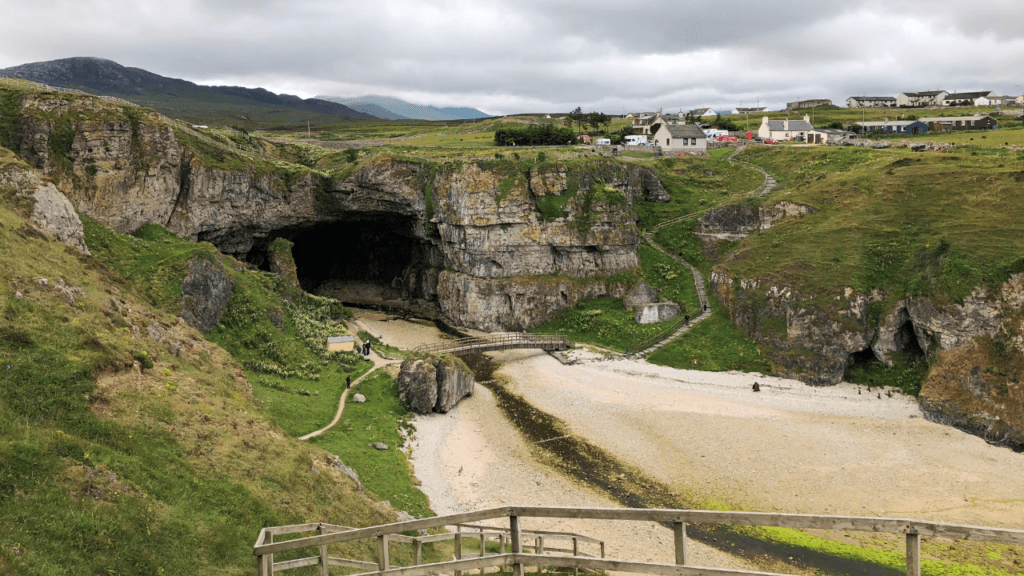Smoo Cave in Durness viewed from on top of the hill, the entrance and wooded path visible. In Sutherland, the North Highlands