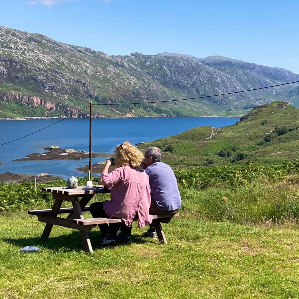 Couple enjoying afternoon tea outside at Newton Lodge Hotel near Kylesku on North Coast 500, West Highlands