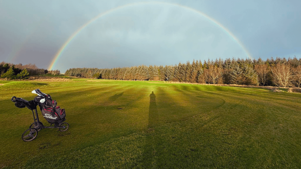 Golf clubs fit on the golf course, with a double rainbow in the sky, Thurso, North Highlands